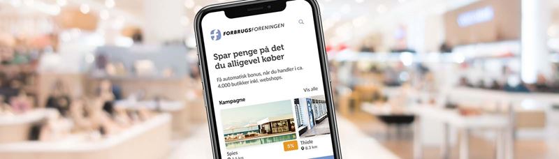 Mobiltelefon der viser Forbrugsforeningens app forside indsat i kontormiljø